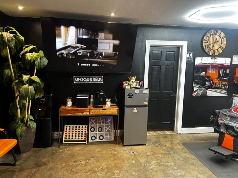Modern home bar setup with black walls, wooden counter, refrigerator, shelving, and decorative plants in a contemporary interior space